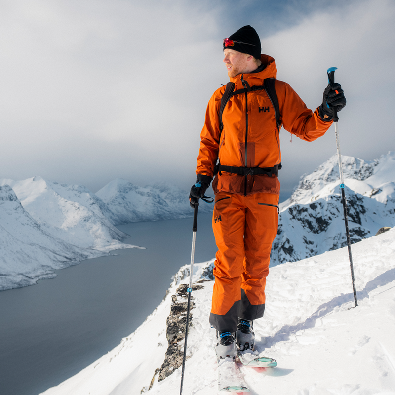Helly Hansen Men's Verglas Backcountry Bib Shell Pants on skier on top of ridge overlooking inlet and mountains