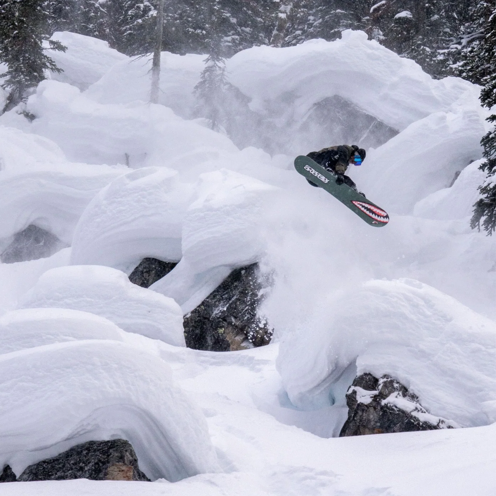 Bataleon Tornado x Beyond Medals with rider in air flying over large snow capped boulders