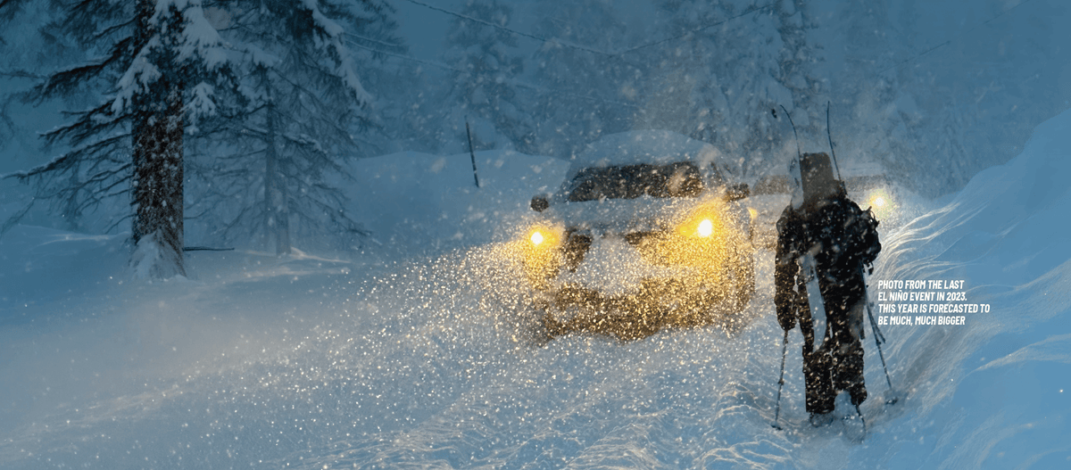 A snowy forest scene at dusk with a person standing in the snow using ski poles, facing an SUV with bright headlights. The scene is heavily snow-covered and atmospheric, with a small block of text describing El Nino snowfall.